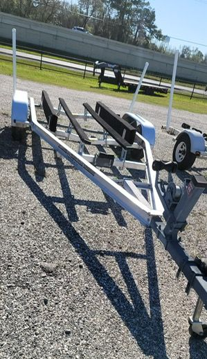 Boat trailer on gravel, with guiding poles and black padded supports.