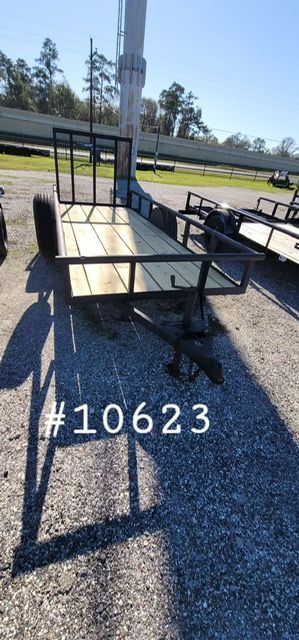 A utility trailer with wooden flooring, metal frame, and a guard. Marked with #10623. Outdoors.