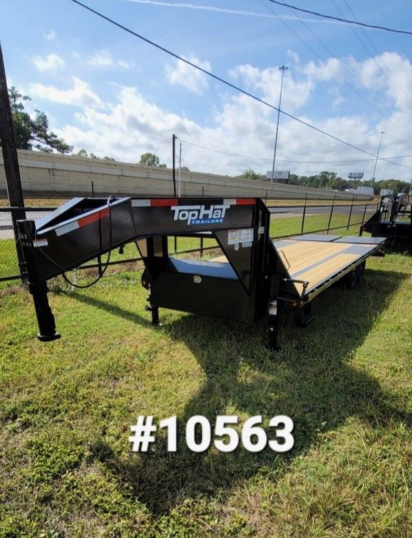 Black Top Hat gooseneck trailer in a grassy area with a highway in the background.