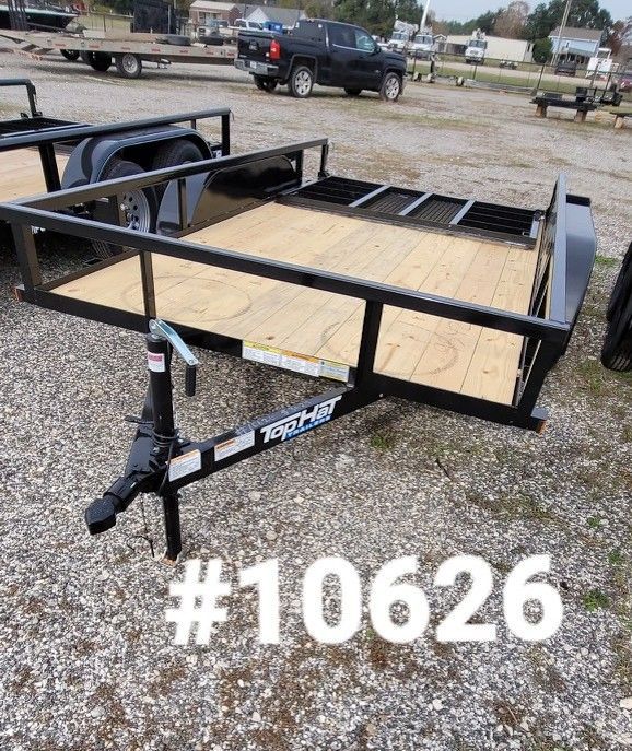 Black utility trailer with wooden deck on gravel, with a truck in the background. Numbered #10626.