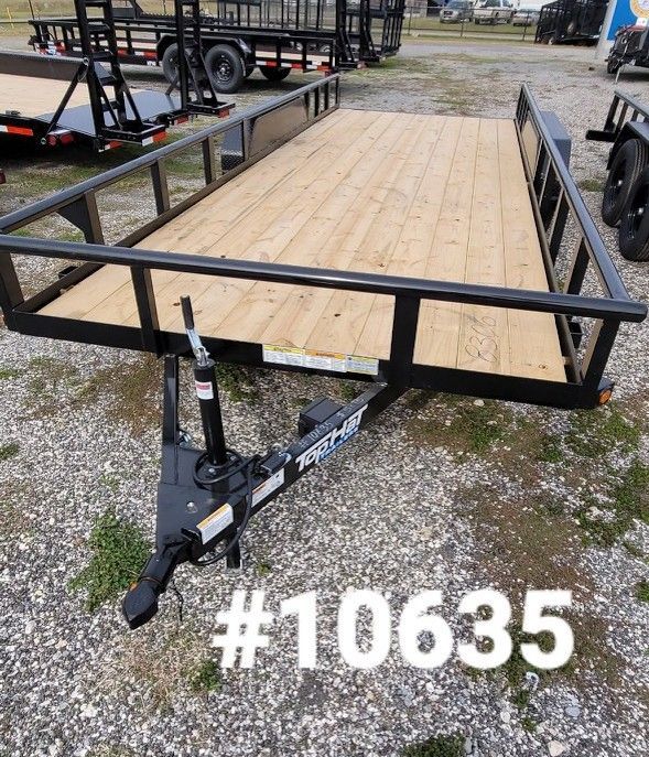 Black trailer with wooden deck, black railing, and a trailer hitch. #10635 in white.