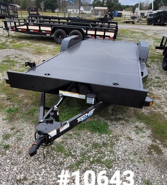 Black utility trailer with wooden deck, on gravel. 