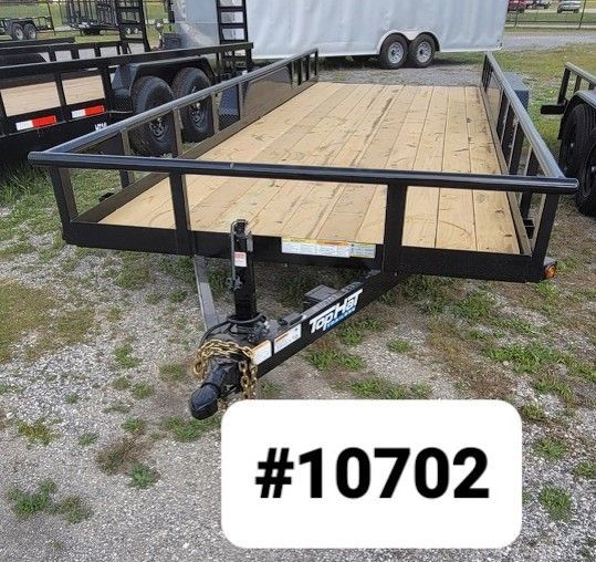A black flatbed utility trailer with a wooden deck sits outdoors, labeled with the number 10702.