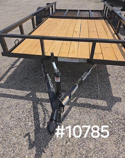 Flatbed utility trailer with black metal rails and a wooden deck on gravel.
