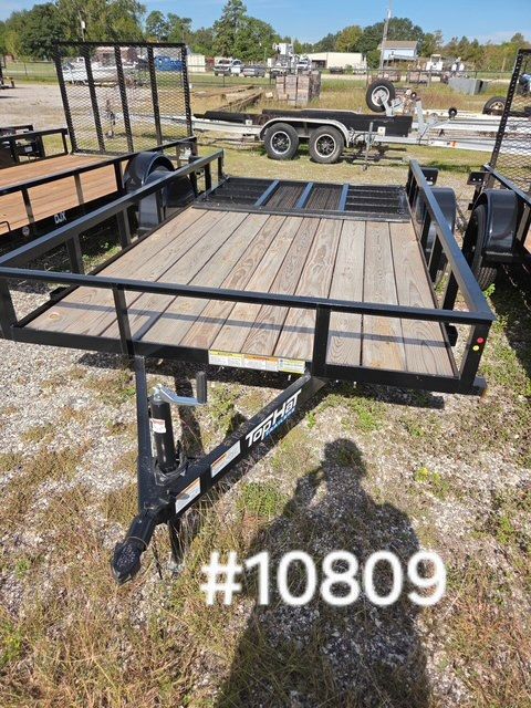 Black utility trailer with wood deck and side rails parked on gravel, labeled #10809