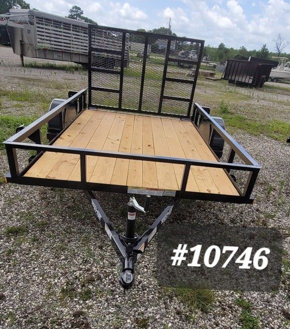 Black utility trailer with wood floor and mesh gate, parked on gravel, labeled #10746