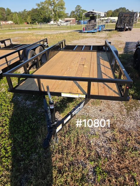 Black flatbed trailer with wooden deck parked on grass, seen from the rear in a yard