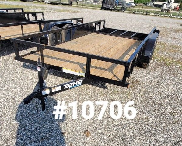 A black utility trailer with a wooden deck parked on a gravel lot, labeled with the number #10706.