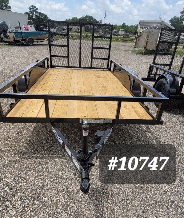 Black utility trailer with wood deck and mesh sides on gravel lot, labeled #10747