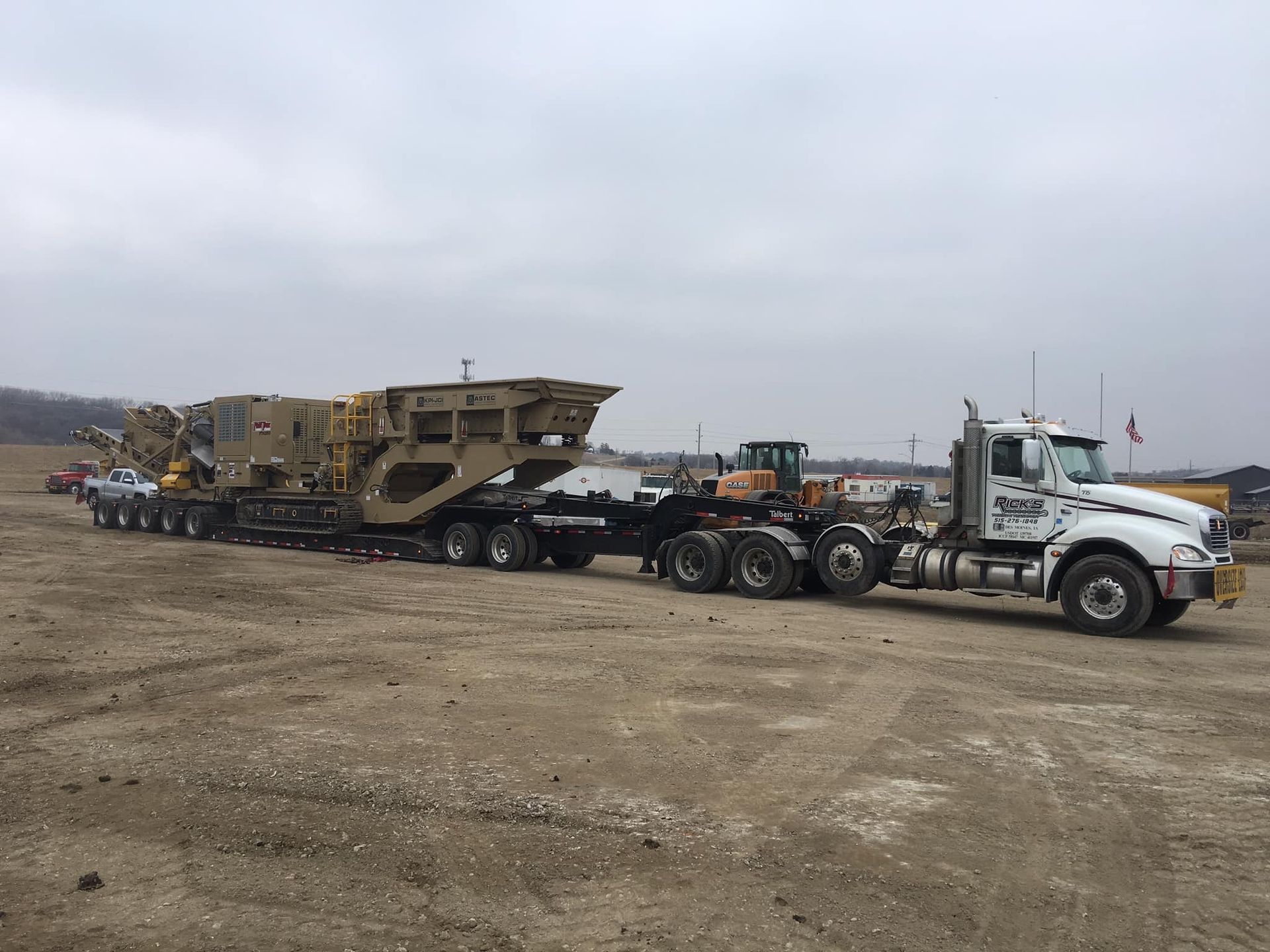 A semi truck is carrying a large piece of equipment on a trailer.
