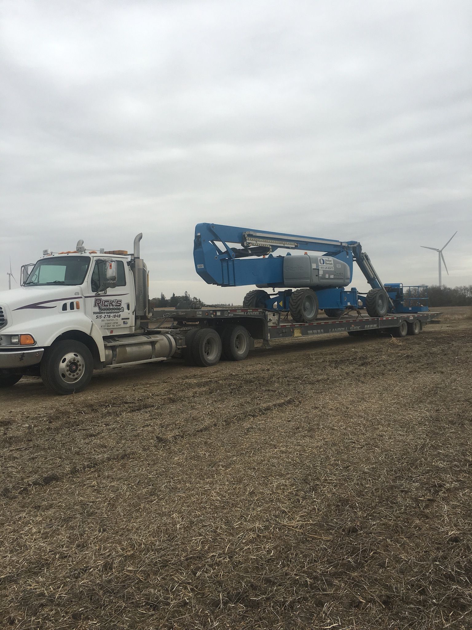 A semi truck is carrying a crane on a flatbed trailer.