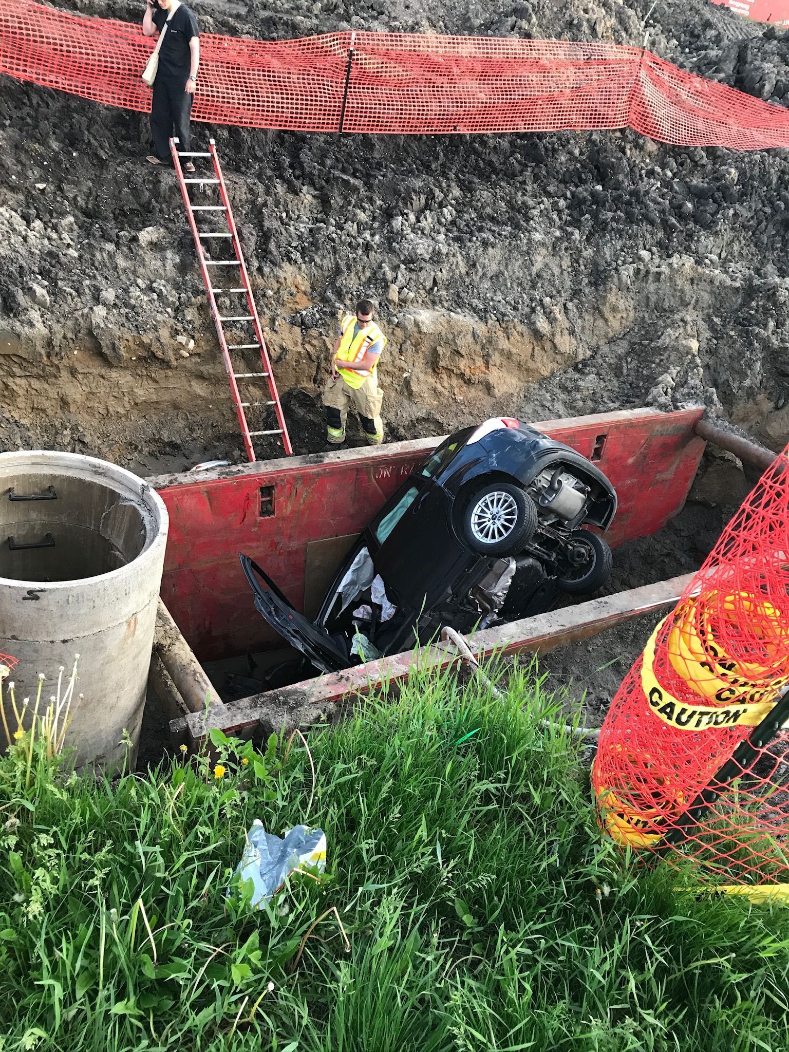 A car is sitting in a wheelbarrow in the dirt.