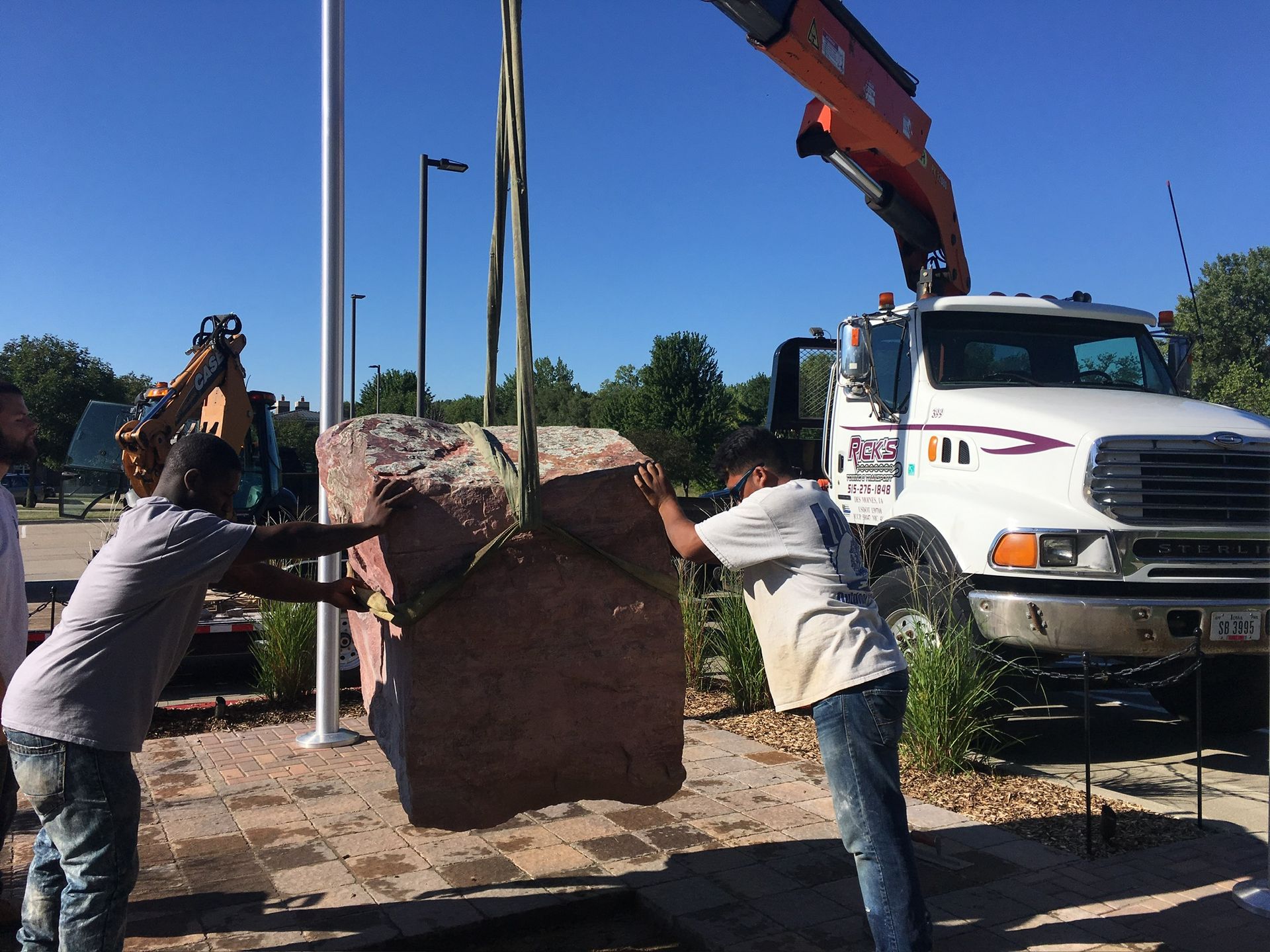 Two men are lifting a large rock with a crane.