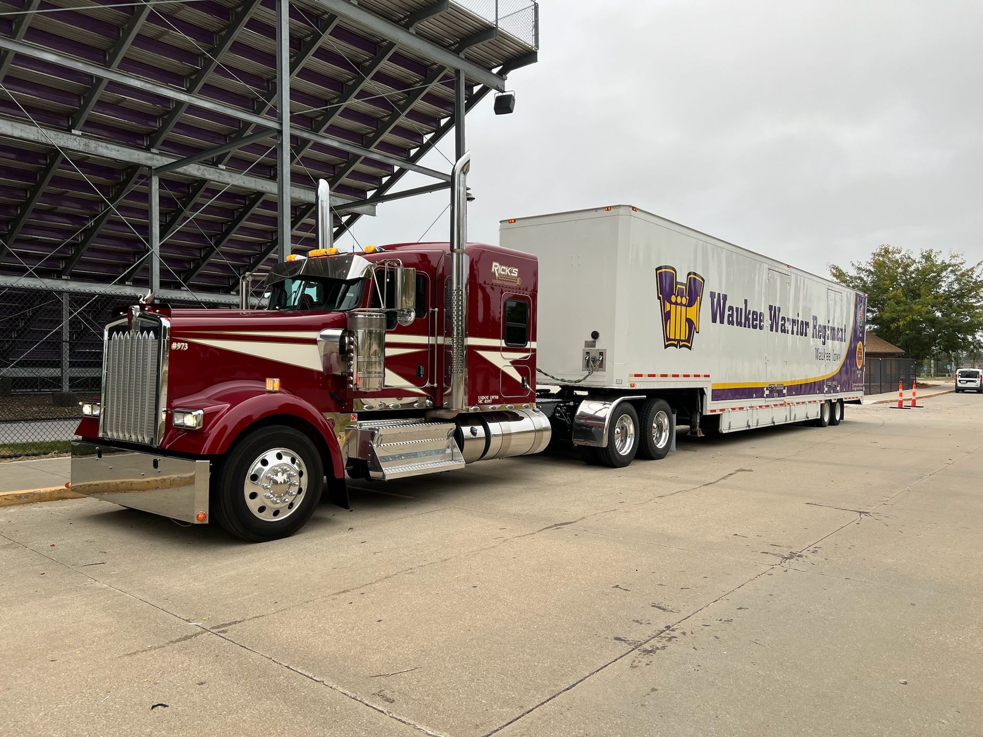 A red semi truck with a white trailer is parked on the side of the road.