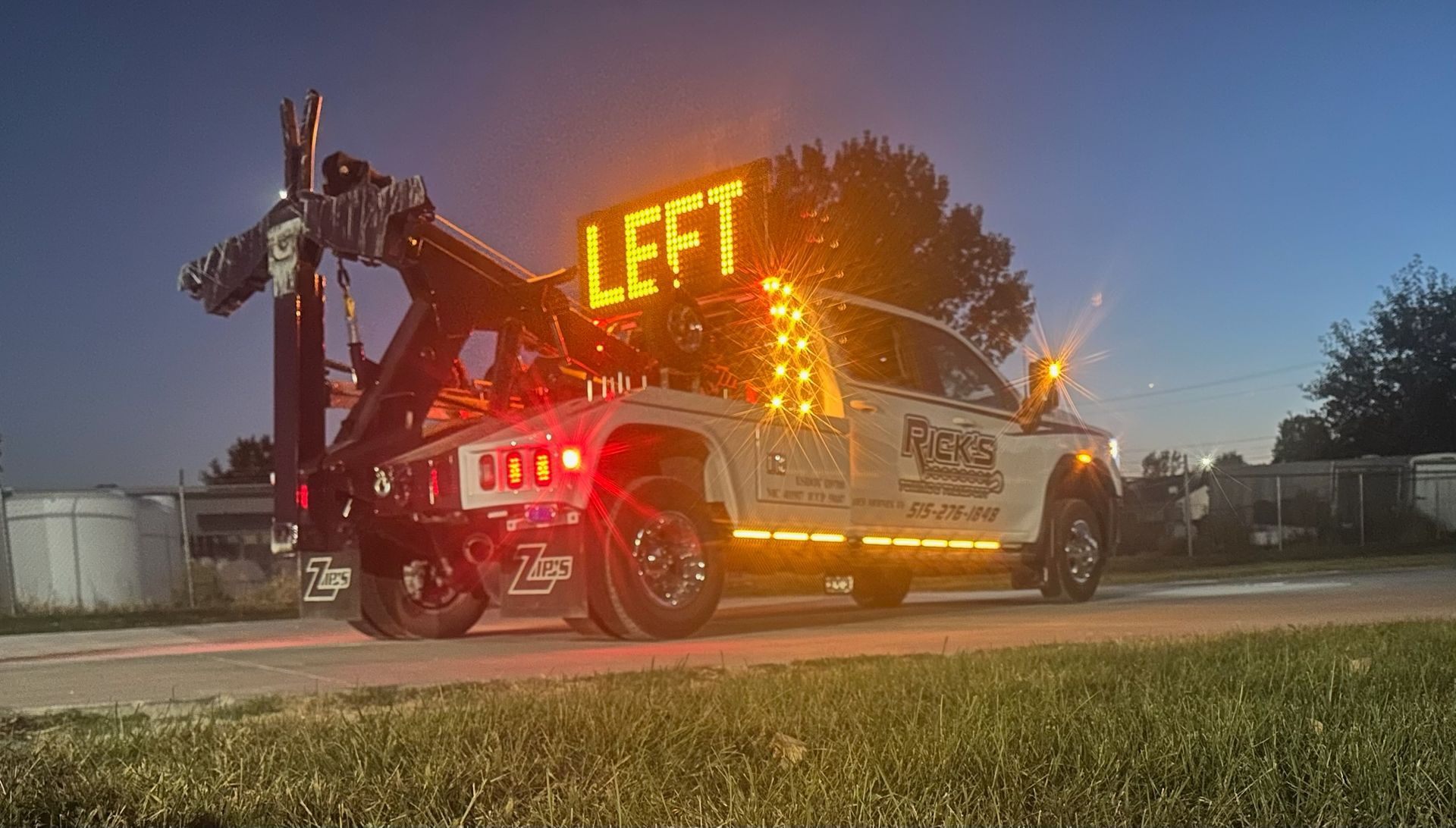 A tow truck is parked on the side of the road at night.