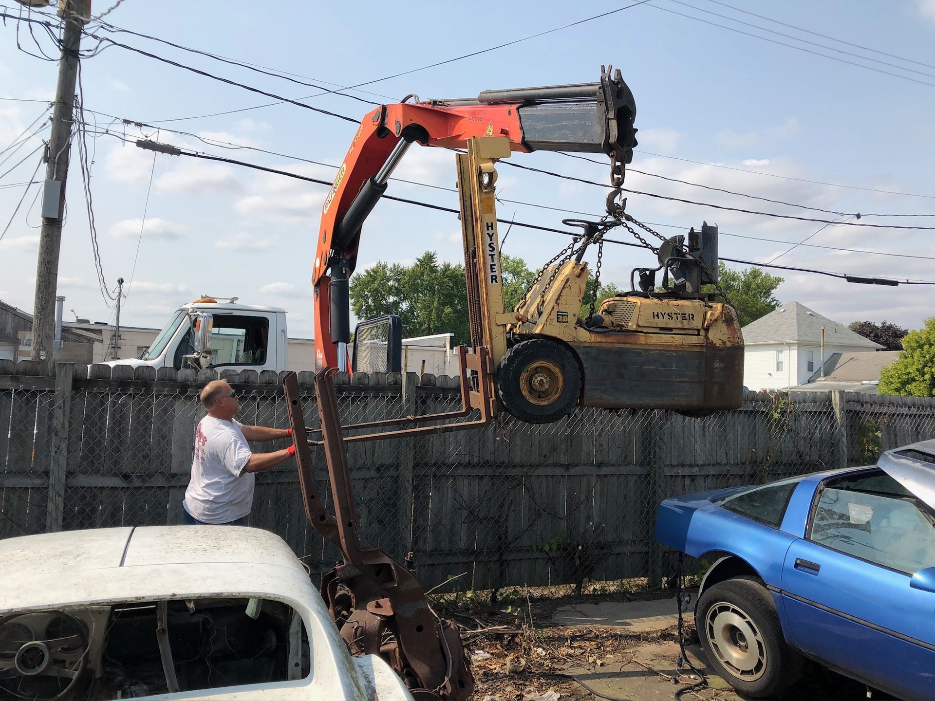 A blue car is being lifted by a crane