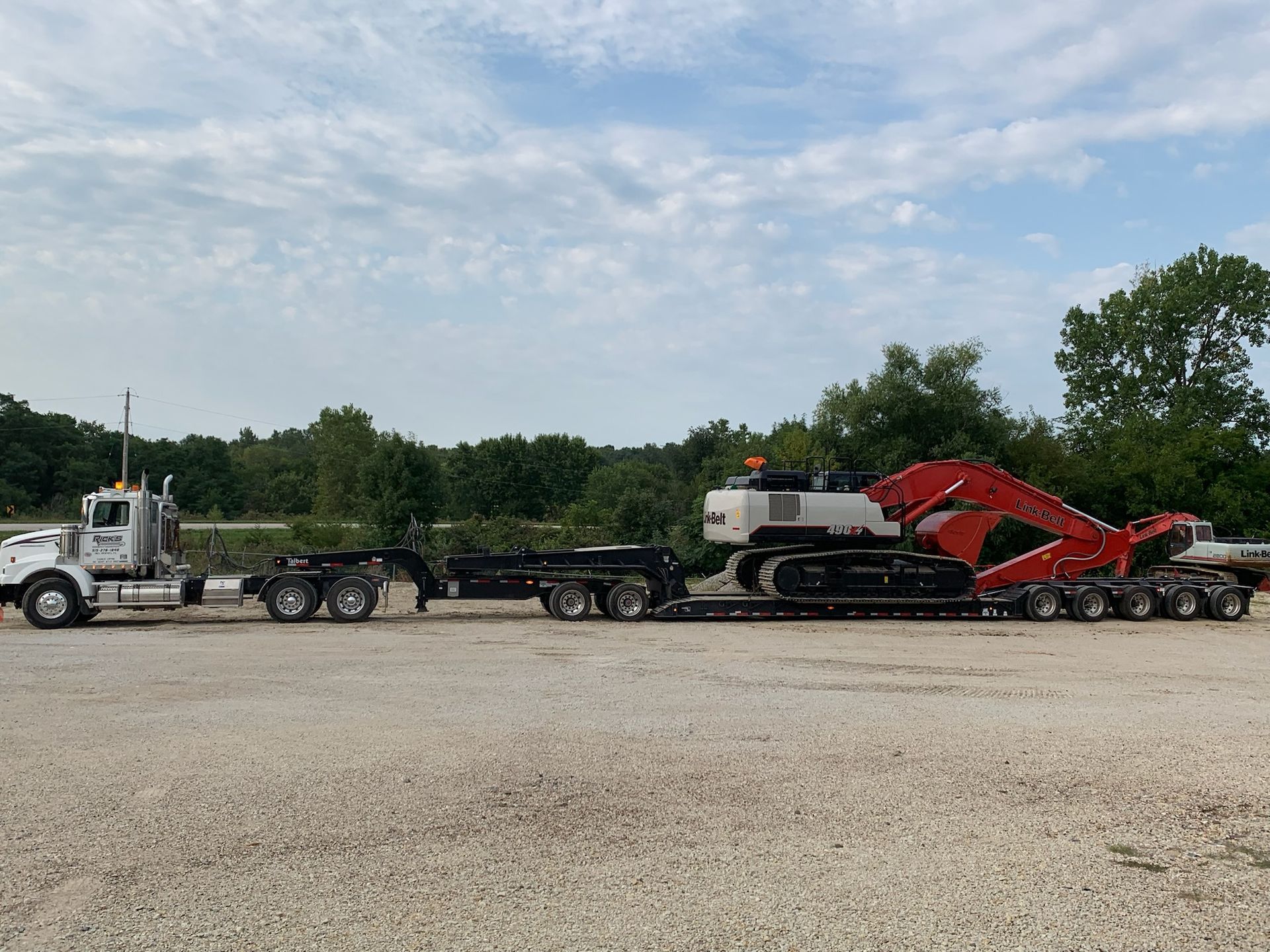 A semi truck is carrying a large excavator on a trailer.