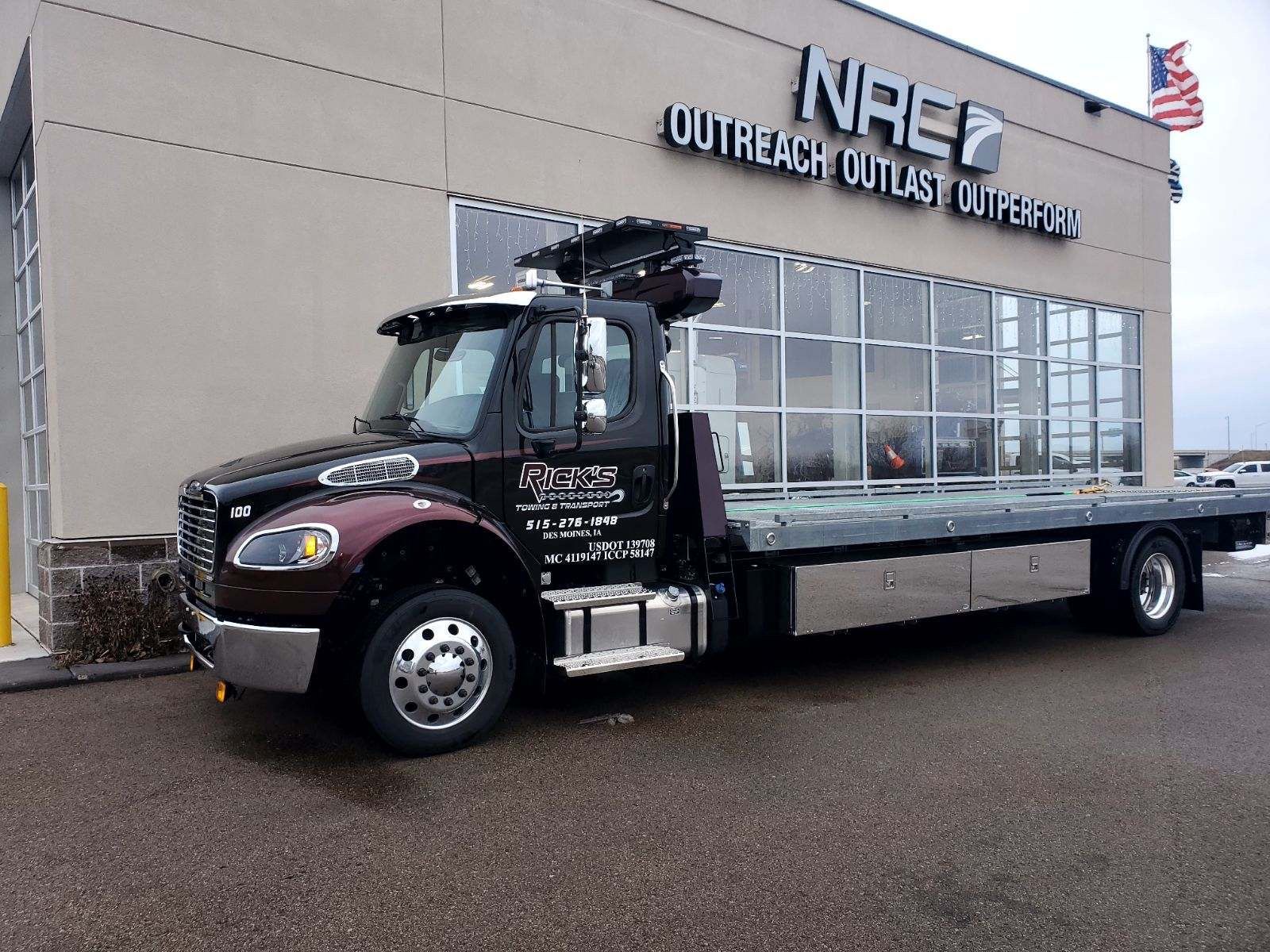 A tow truck is parked in front of a building that says nace