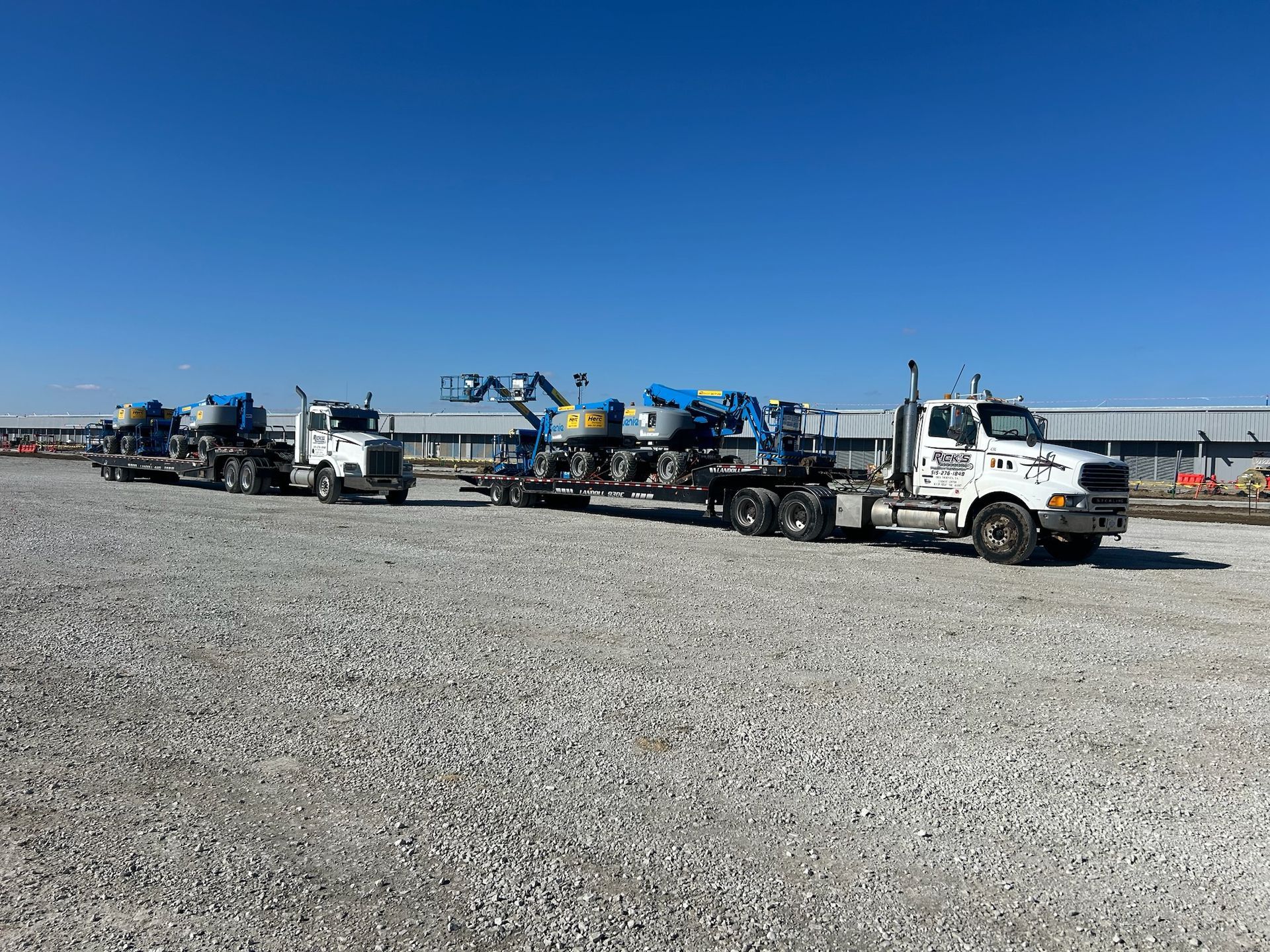 A row of trucks are parked in a gravel lot.