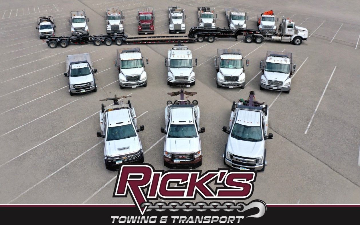 A group of Rick 's towing trucks are lined up in a parking lot