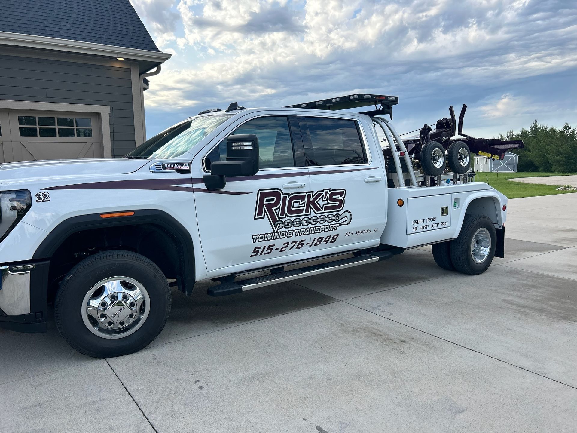 A white tow truck is parked in front of a garage.