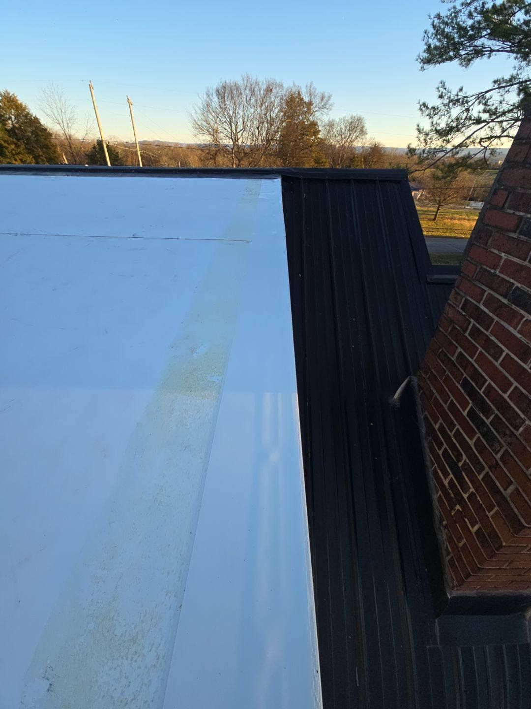 White and black rooftop with a brick chimney in a sunny outdoor setting.