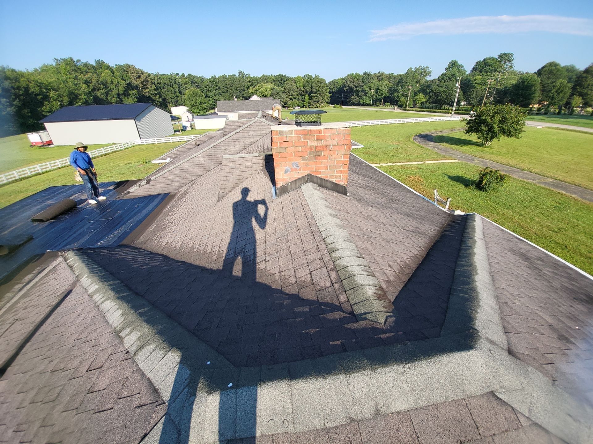 Person on a roof with a chimney, preparing for roofing work. Sunny day.