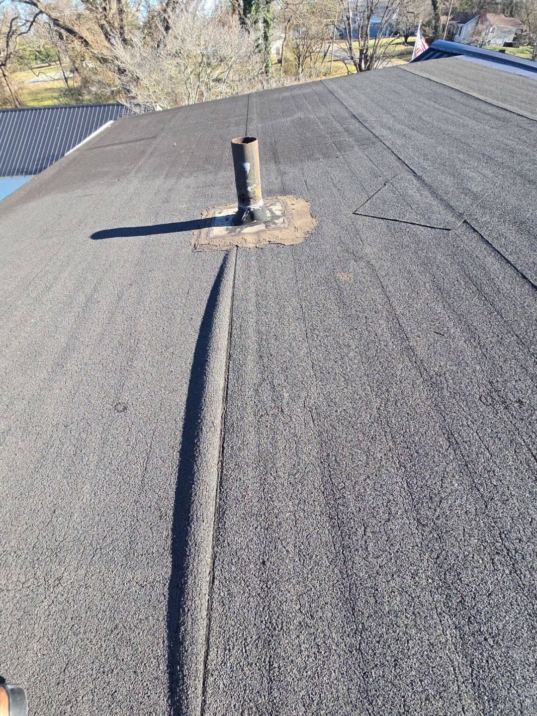 Dark gray asphalt roof with a vent pipe; sunny outdoor setting.
