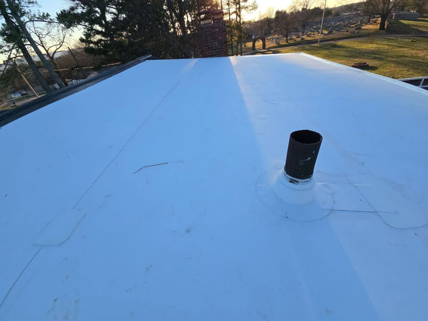 White flat roof with black vent pipe, outdoors.