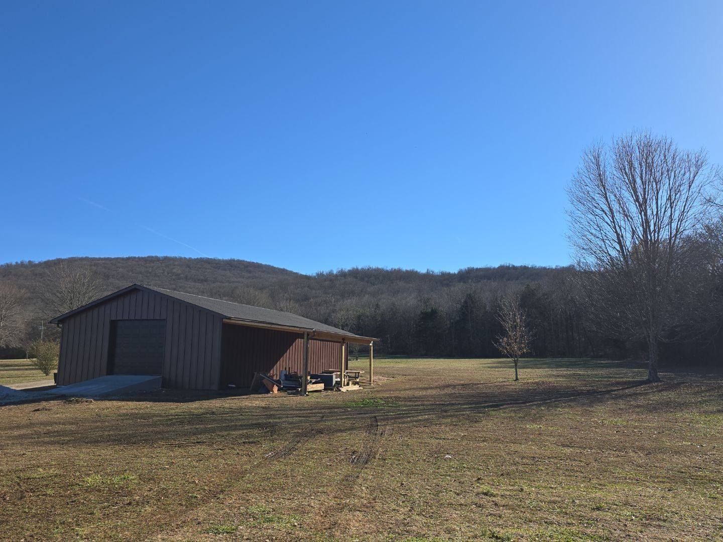 Barn in a field on a sunny day with a mountain in the background.