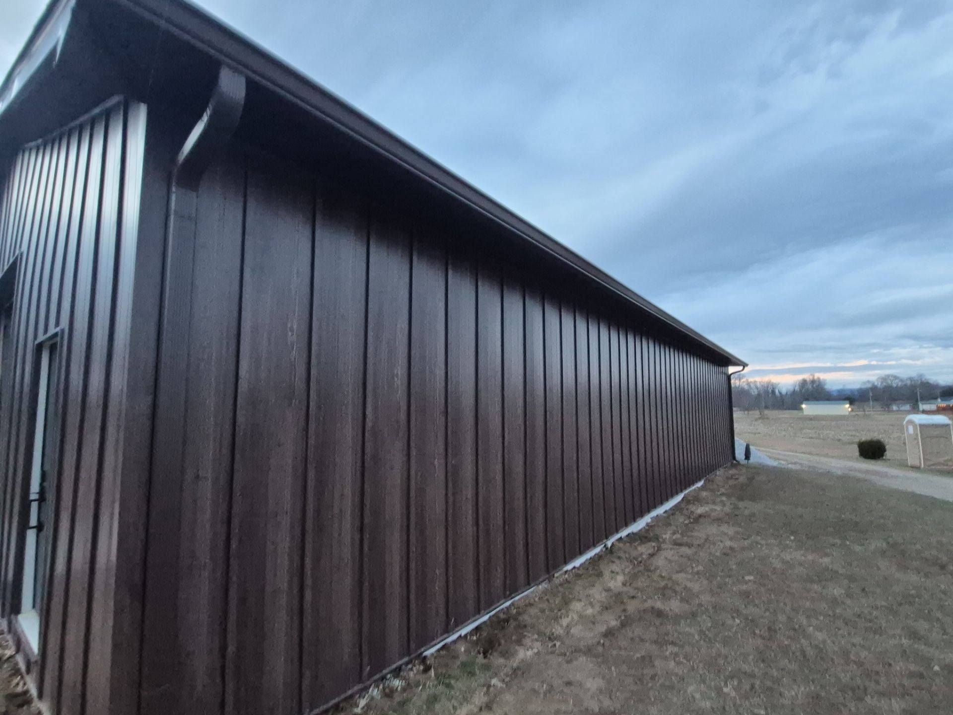 Brown building with vertical siding under a cloudy sky.