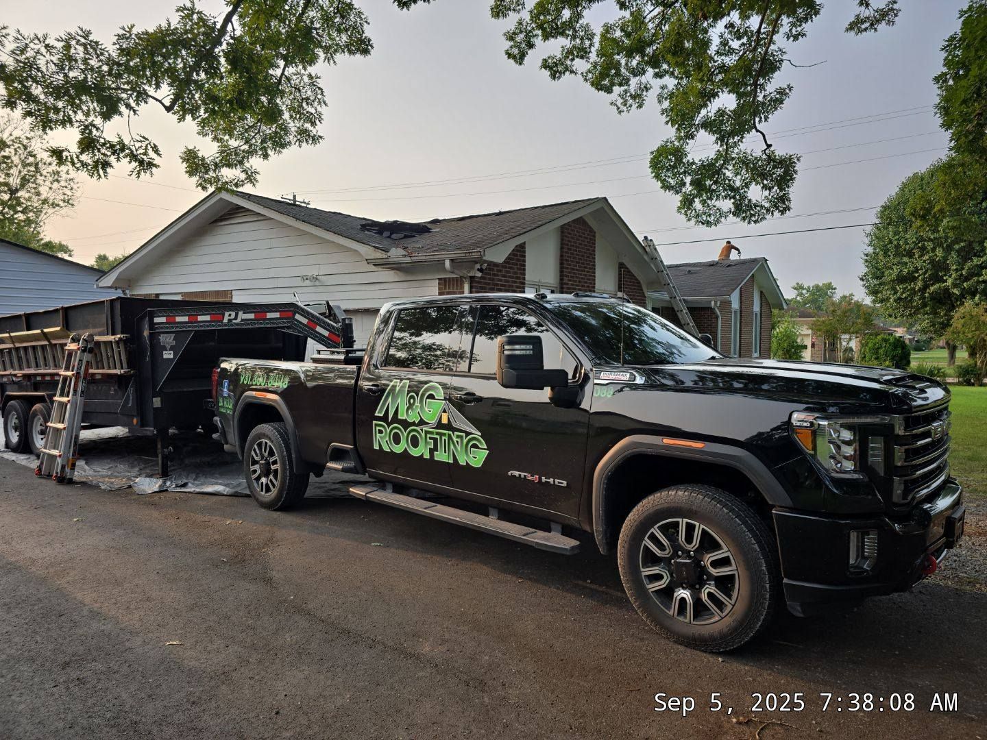 Black pickup truck with a trailer, parked in front of a house, advertising 