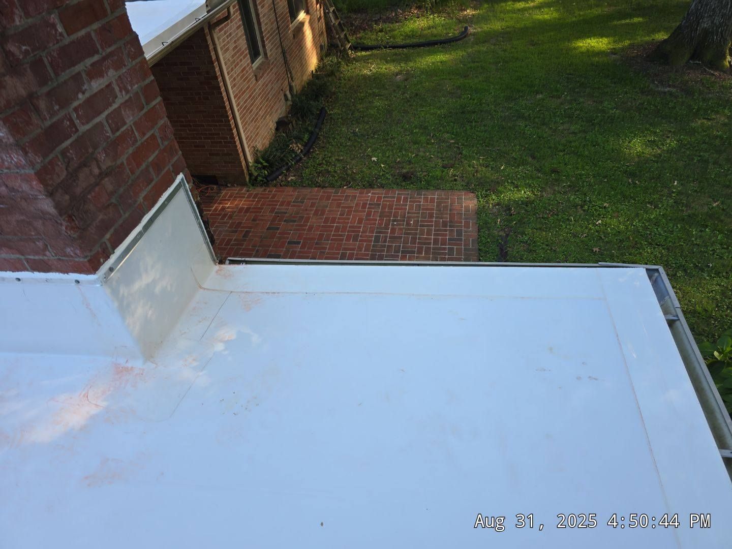 White roof with brick house, and green lawn.