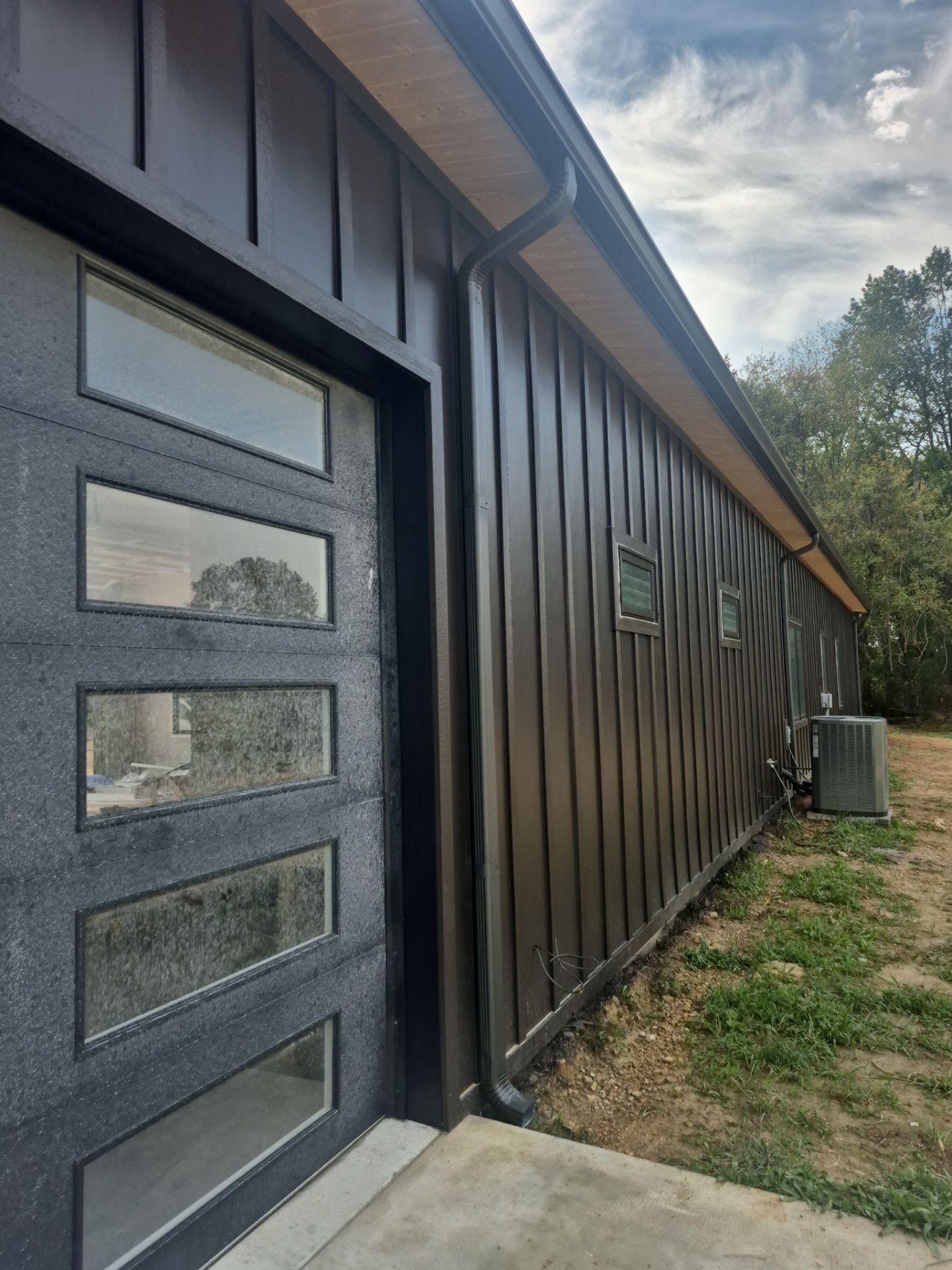 Black metal-sided building with a modern door with glass panels and a window.