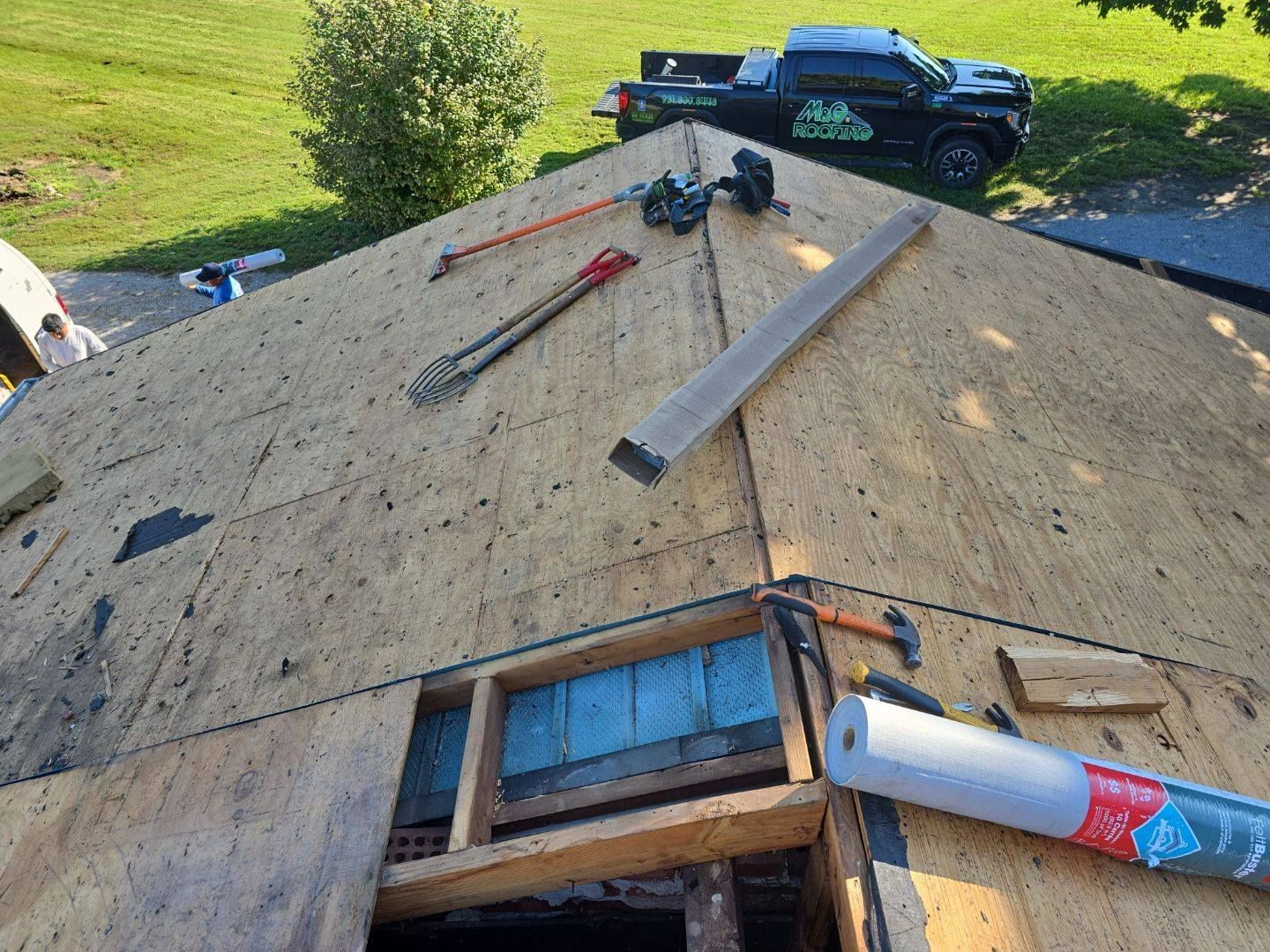 Roof under construction, tools scattered. Truck parked nearby.