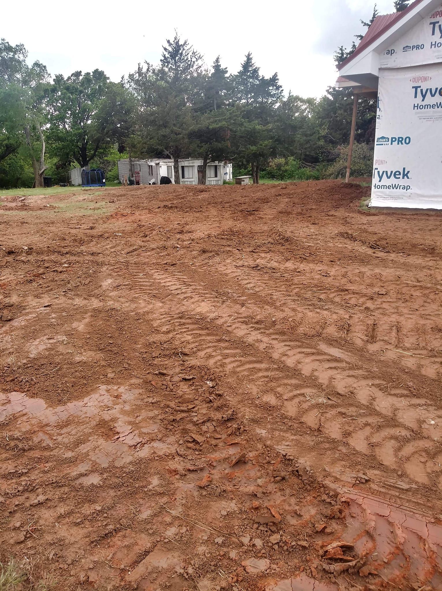 A large pile of dirt is in front of a house under construction.