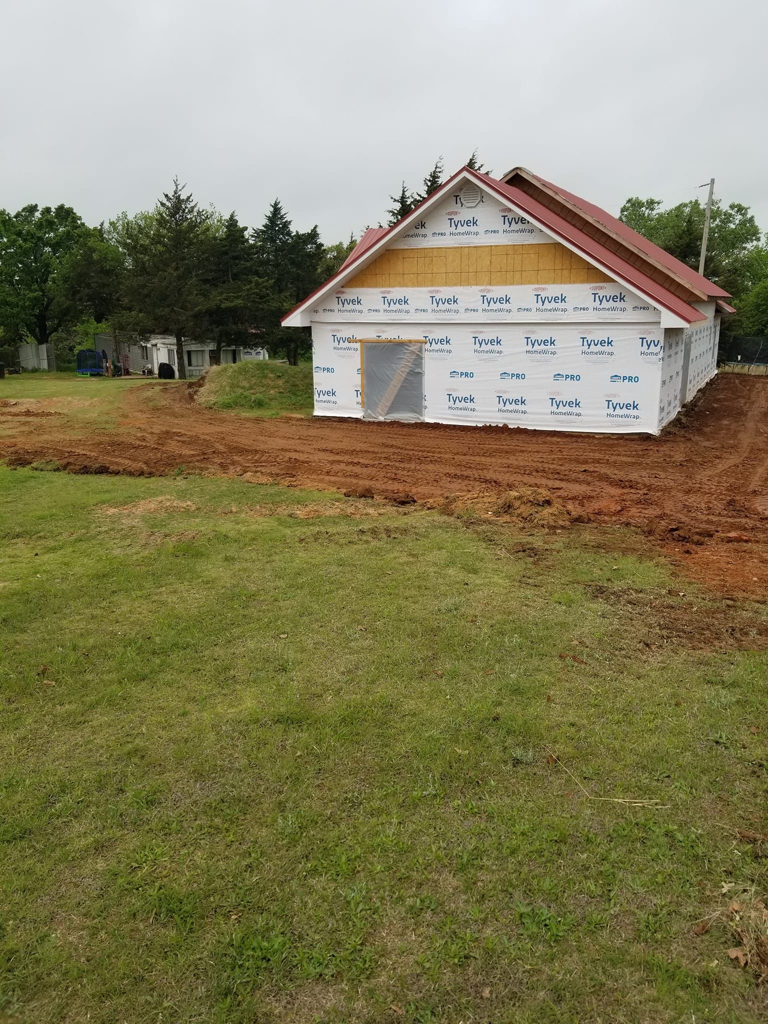 A small house is being built in the middle of a grassy field.