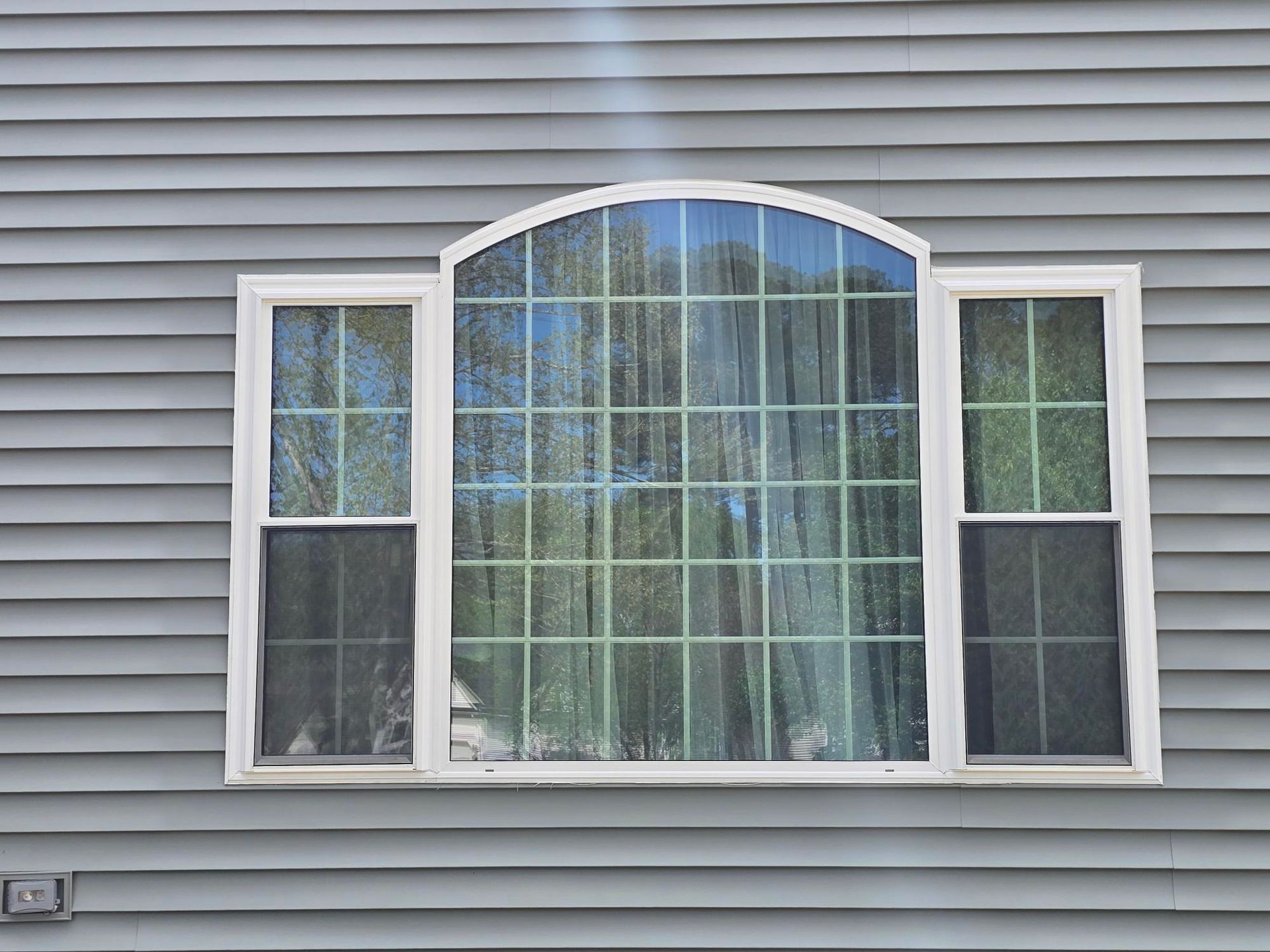 White house siding with a centered arched window and two narrow side windows