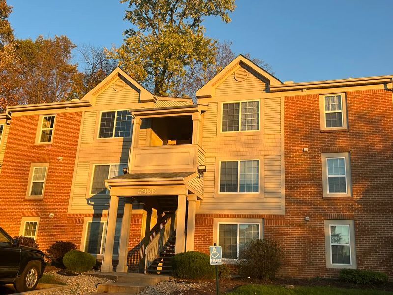 A large brick apartment building with a car parked in front of it
