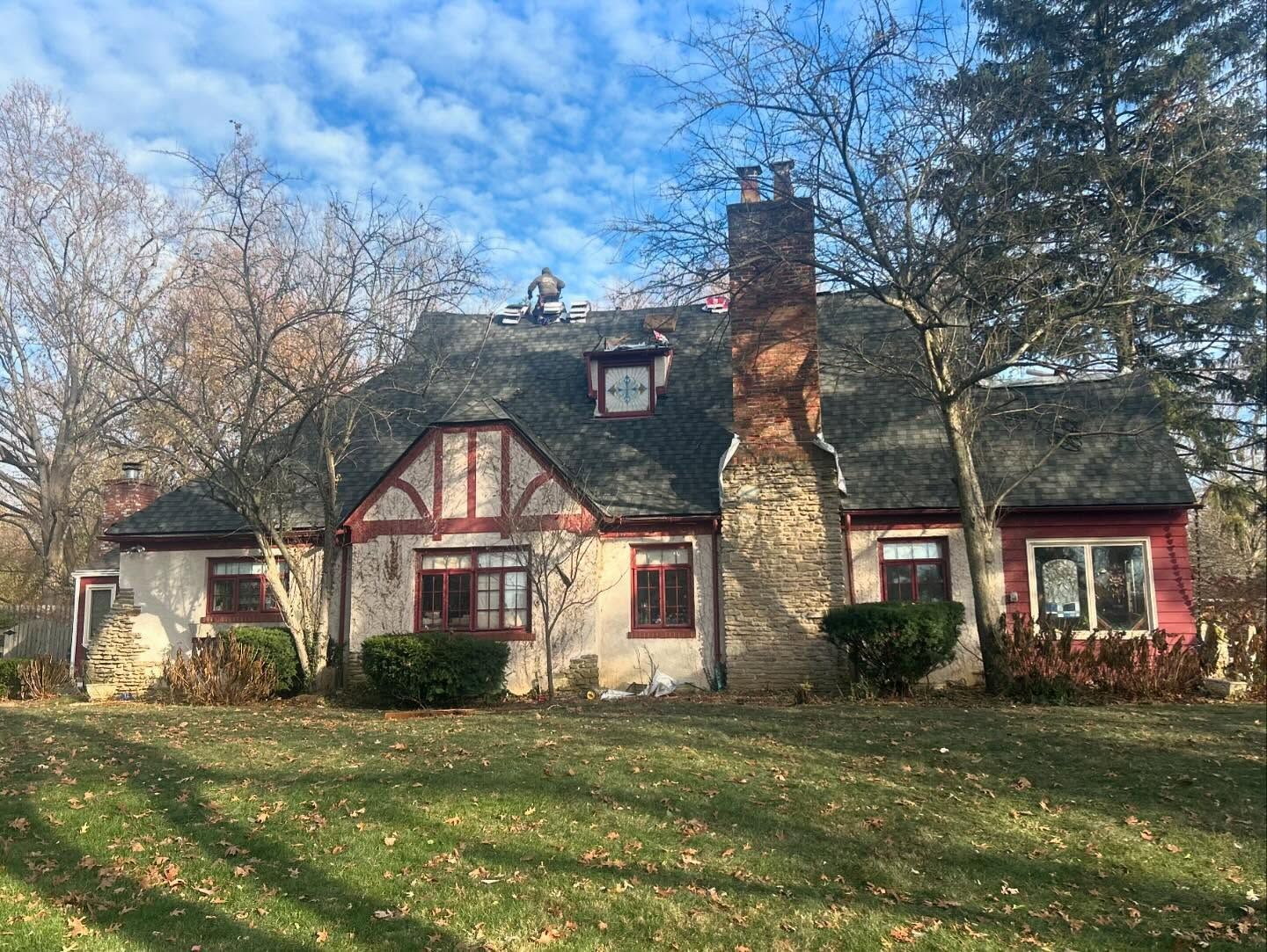 A large house with a gray roof is sitting on top of a lush green field.