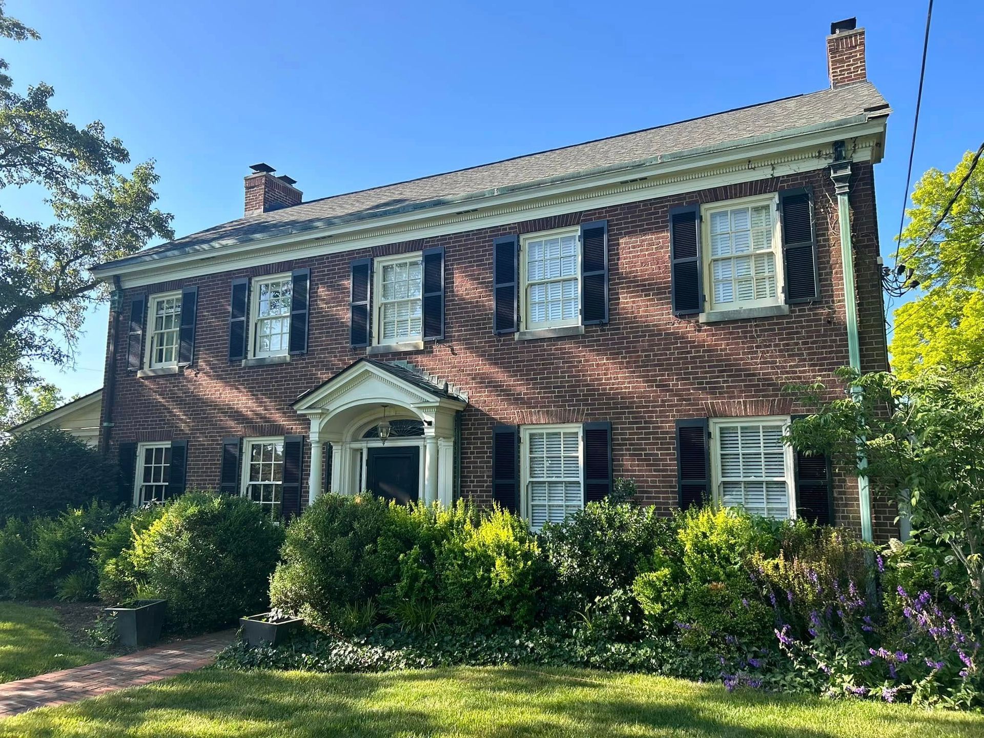 A large brick house with black shutters on the windows