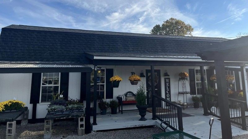 A white house with a black roof and a porch.