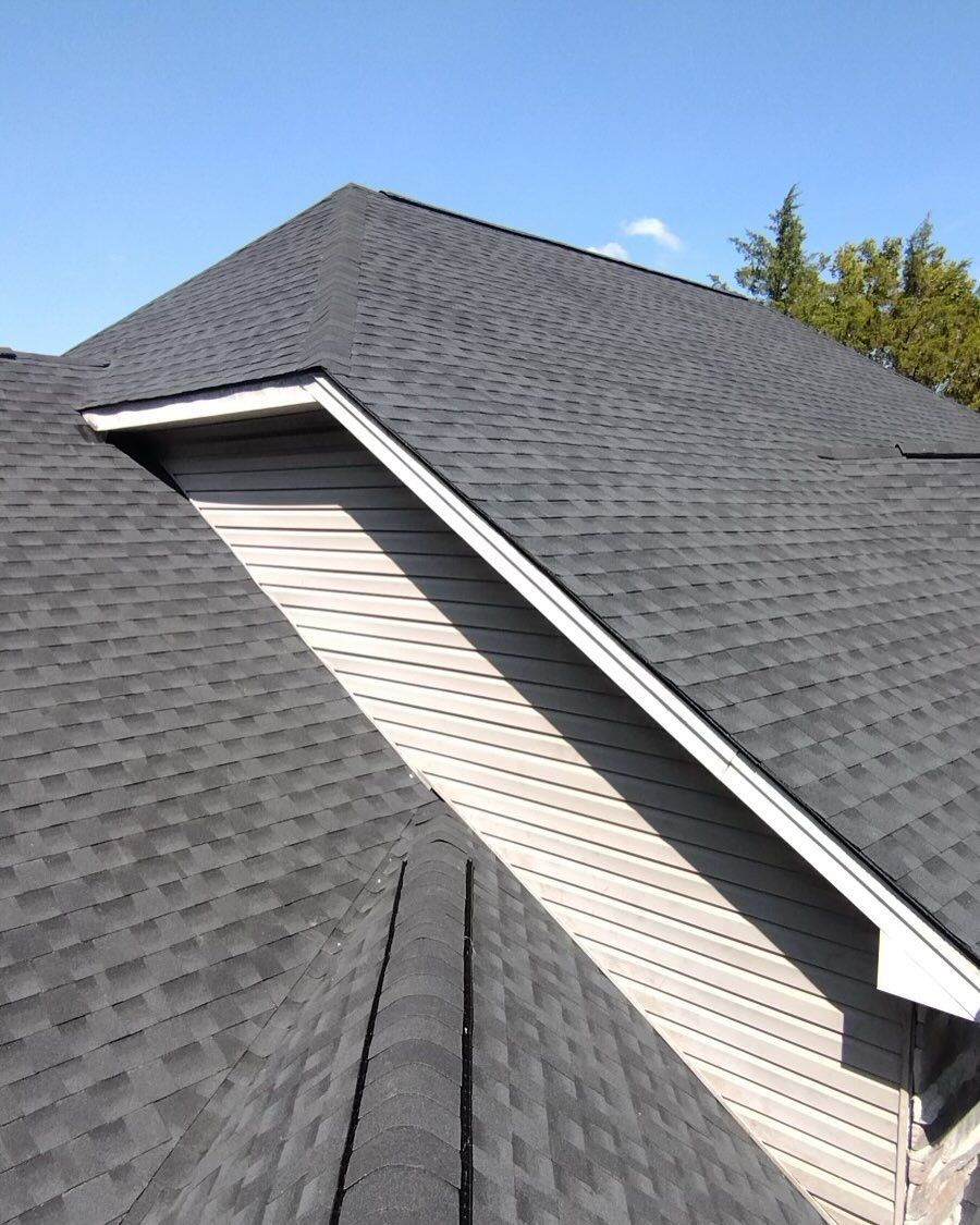 A house with a black roof and a white siding