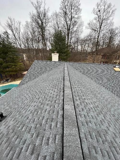 A roof with a chimney on it and a pool in the background.