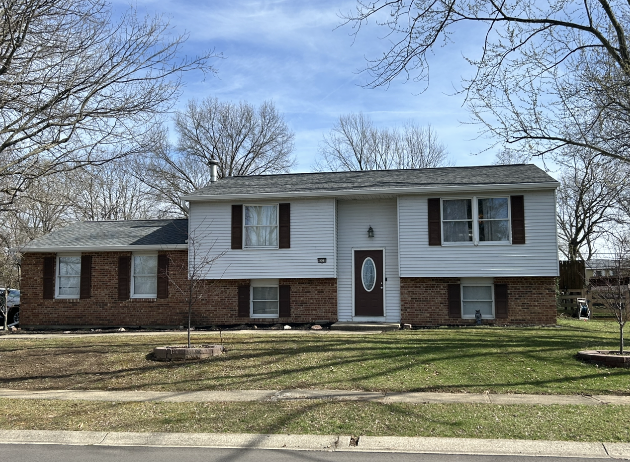 A large white house with brick walls and black shutters is sitting on top of a lush green lawn.