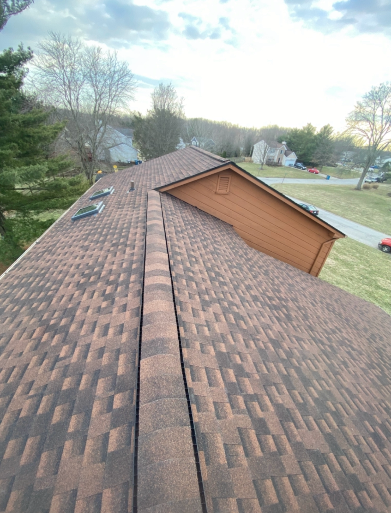 A roof with a lot of shingles on it and a house in the background.