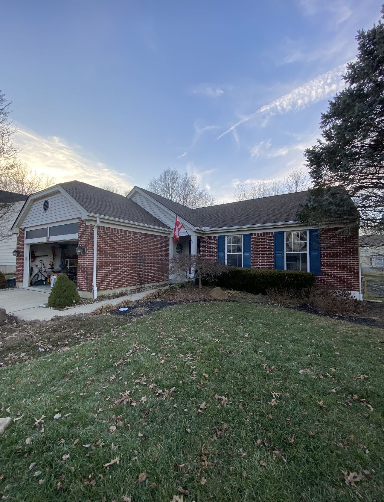 A brick house with blue shutters and a large lawn in front of it.