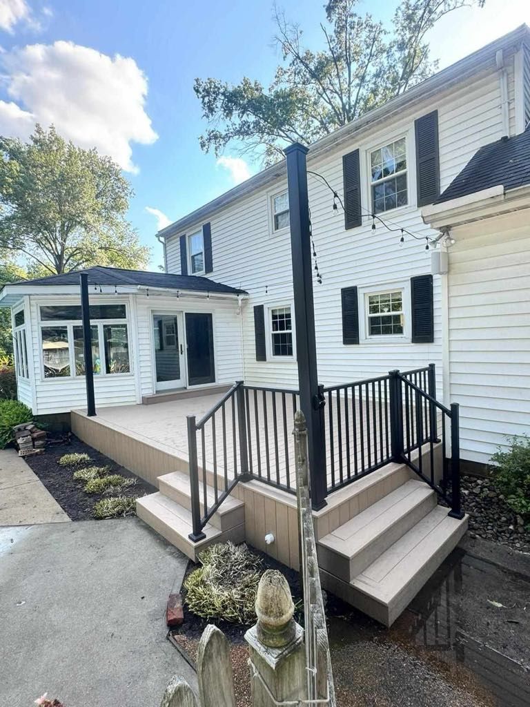 White house exterior with new front ramp, stairs, black railings, and a screened porch