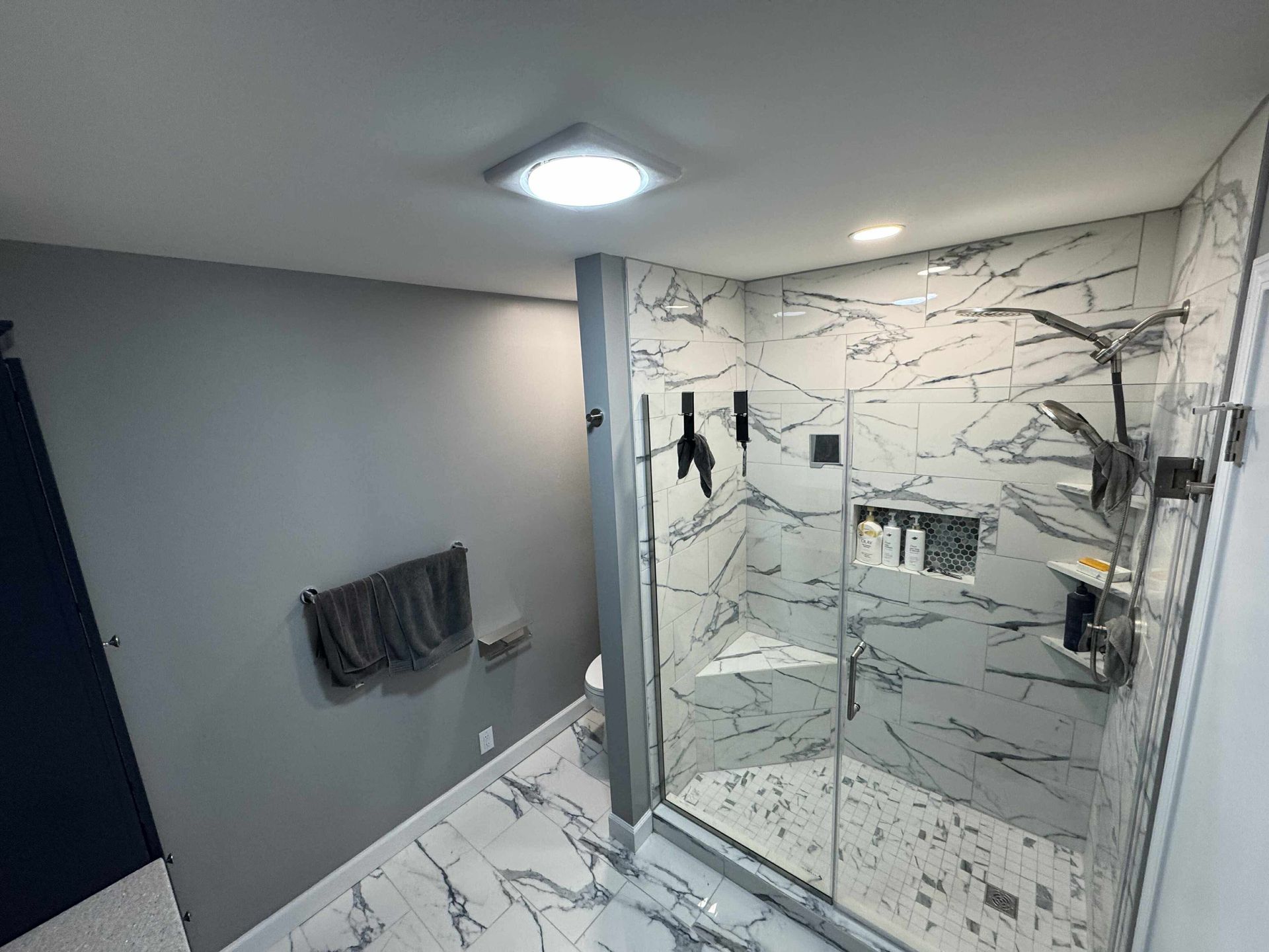 Modern bathroom with gray walls, marble tile, and a glass walk-in shower with a rainfall showerhead