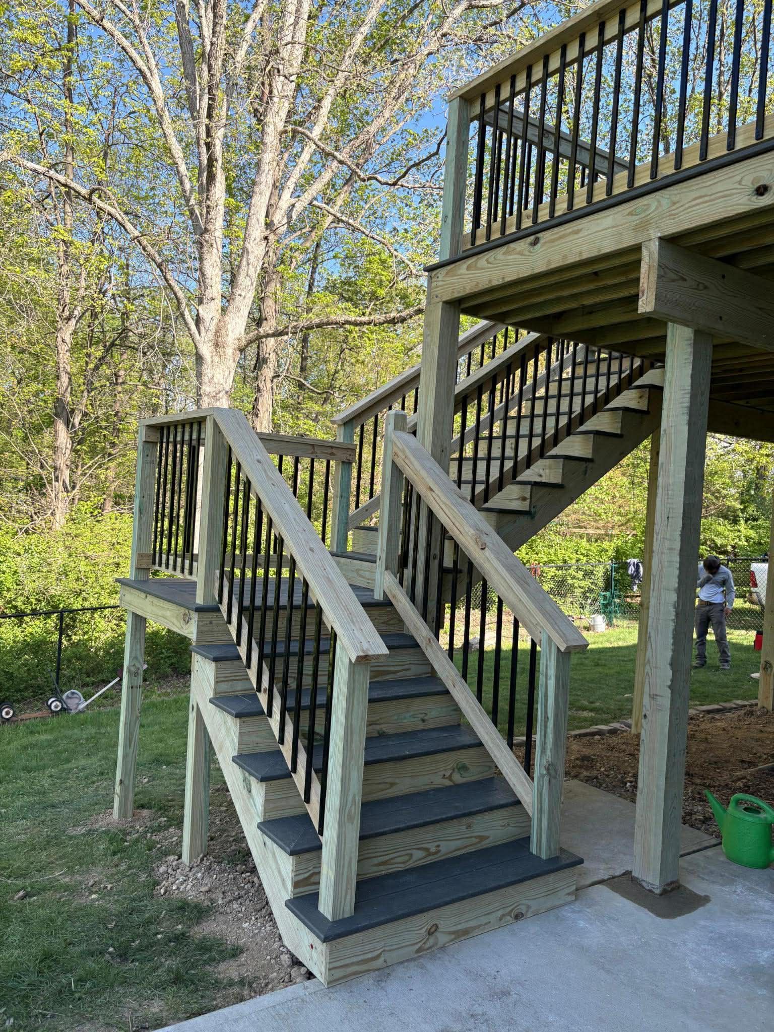 Wooden outdoor staircase with railings leading to a raised deck in a grassy yard